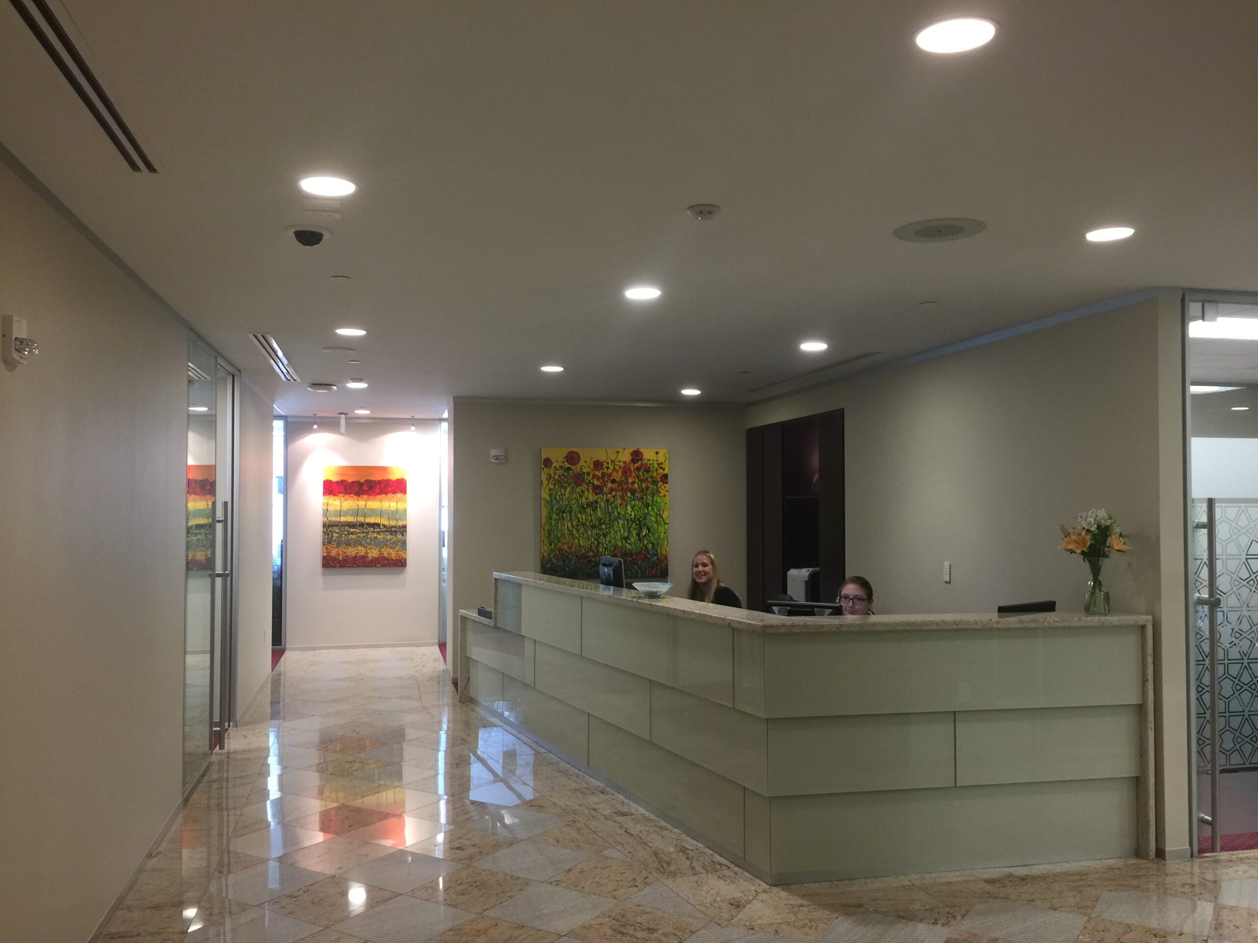 A large lobby with a reception desk and paintings on the wall.